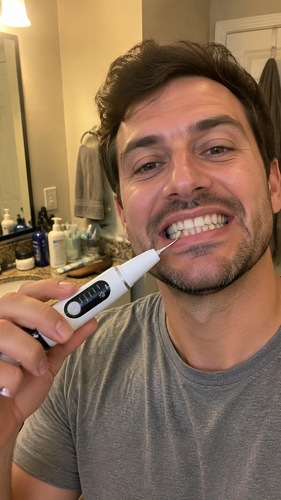 Man using the ultrasonic cleaner on his lower front teeth in the bathroom