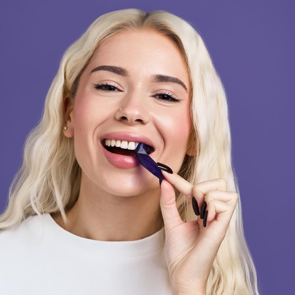 A woman putting on a MOON purple whitening strip